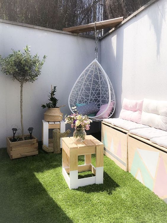 a small and fun pation with lawn, with a storage sofa, some side tables, potted greenery and a pendant egg chair
