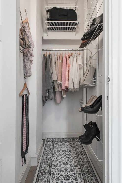 A small and narrow closet with a bit of open storage space and metal shelving, some clothes hangers on the wall is well organized