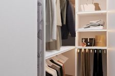 a small and narrow minimalist closet with open storage units, lit up shelves and some boxes on top doesn’t look cluttered and is well-organized