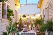 a small and welcoming patio with a dining set and a sofa with side tables, potted greenery and candles is an inviting space