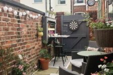 a small backyard with potted plants and blooms, some furniture, a clock and some decor and accessories