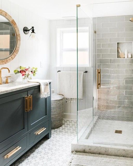 a small bathroom with grey long tiles and printed ones on the floor, a graphite grey vanity, touches of gold and a marble countertop