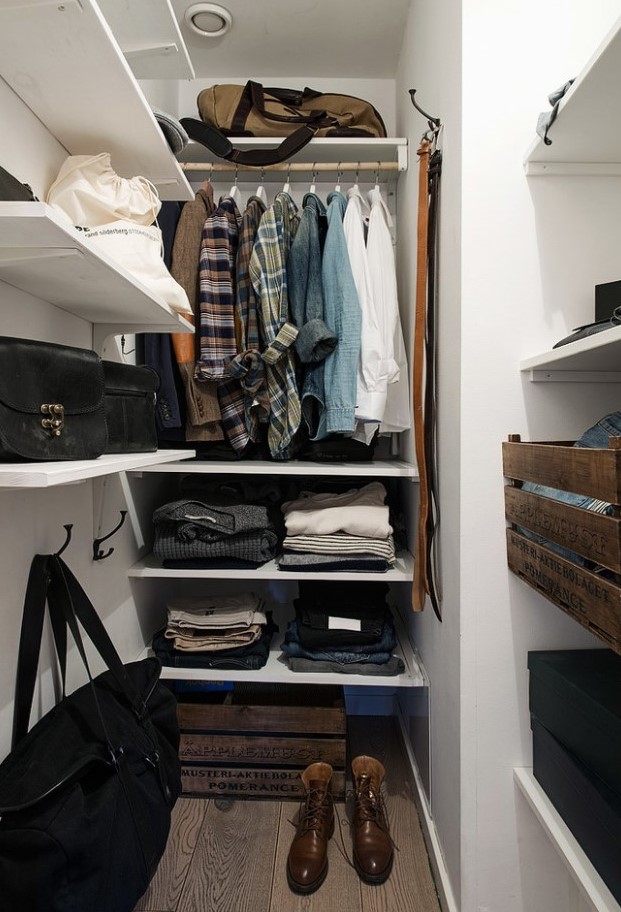 A small closet with wall mounted and built in shelves, a rack for hanging clothes, some crate drawers and boxes for shoes