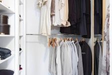 a small contemporary closet with holders for hangers, open shelves for various stuff, a basket and a large mirror