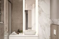 a small minimalist bathroom with marble tiles, a shower space, a floating vanity and a tall mirror with lights