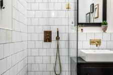 a small monochromatic bathroom with white and black hex tiles, a black vanity and a black frame mirror plus touches of gold