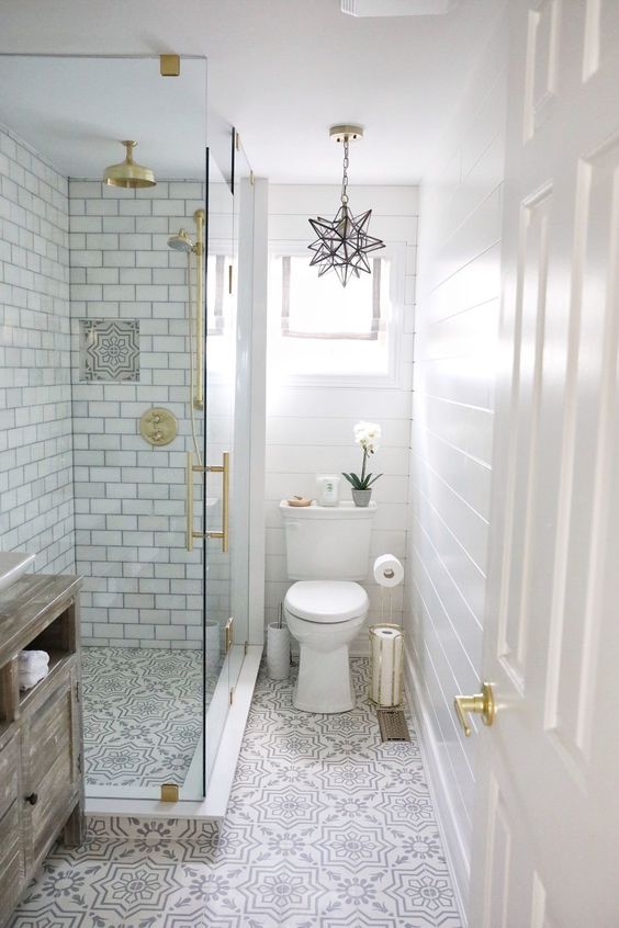 a small peaceful bathroom with white subway tiles, pritned floor, touches of gold and a star-shaped pendant lamp