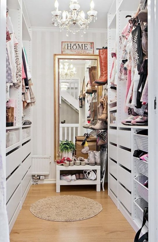 A small vintage inspired sweet closet with a large mirror, a crystal chandelier, open shelves and holders plus drawers