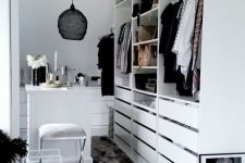 a small white closet with holders, shelves and lots of drawers, with a tiny table for makeup and a black pendant lamp