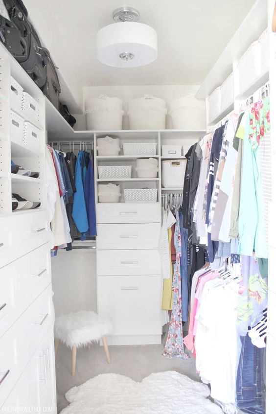A small white closet with open shelves and baskets and boxes, built in drawers and rails for clothes is a cool idea