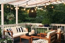 a small yet cozy patio with a sofa and chairs, a leather ottoman, potted blooms and greenery, lights and candle lanterns
