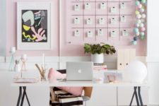a stylish contemporary home office with light pink walls, a gallery wall with a calendar, a lightweight desk and pink accessories