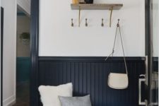 a stylish entryway with midnight blue beadboard, a navy bench, printed tiles on the floor and a bright printed ottoman