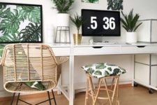 a tropical home office in neutrals, with a tropical gallery wall, potted plants, a rattan chair and stool and touches of gold