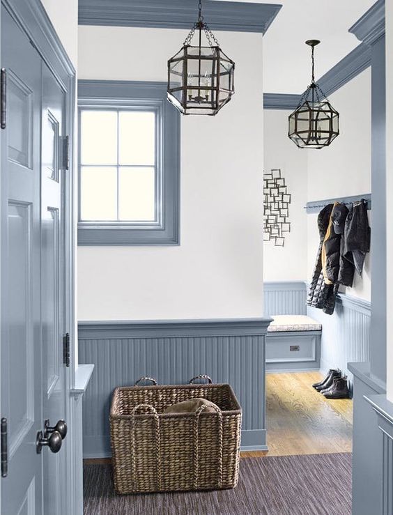 a vintage farmhouse entryway with light blue beadboard, pendant lamps, a basket box and much natural light