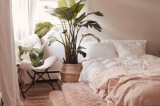 a welcoming contemporary bedroom with blush walls, blush and white bedding, a pink rug, a statement potted plant and tropical pillows
