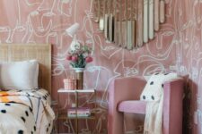 a whimsical pink bedroom with printed wallpaper, a bed with a cane headboard, a pink chair, a rug and a creative mirror