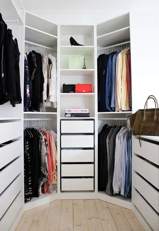 A white hexagon shaped closet with drawers and open shelves and a window is a lovely space to store clothes and shoes