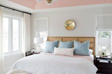 an elegant modern bedroom with a pink ceiling and color block ottomans, blue pillows and touches of gold