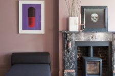 02 The living room features mauve walls, a mini hearth in the non-working fireplace and catchy artworks