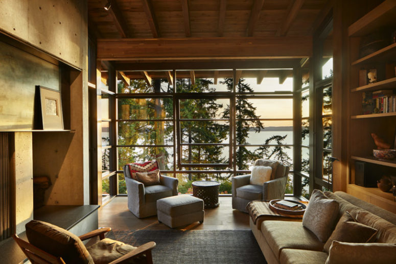 The living room shows off a glazed wall with forest and coastal views, a built-in fireplace and modern furniture