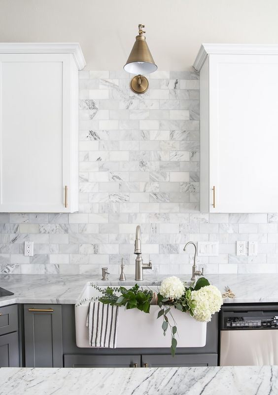 Two toned gray and white cabinets, marble subway tile, Carrara countertops, a big farmhouse sink, and brass hardware for a farmhouse kitchen