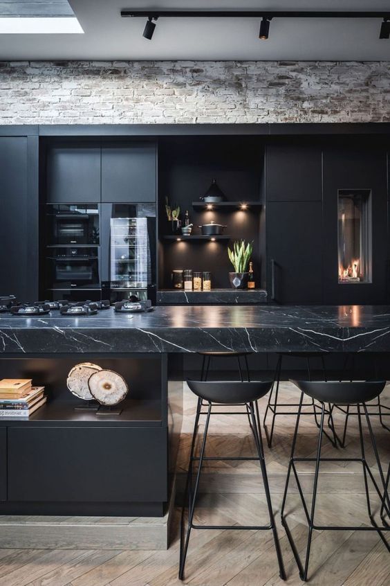 a black moody kitchen with plain cabinets and a stunning black marble kitchen island for a refined feel
