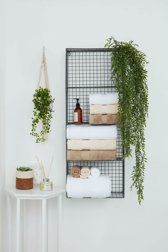 a metal wall shelf for storing towels, soaps, greenery in pots is a nice solution to save some floor space