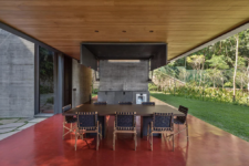 04 There’s an outdoor kitchen done with metal and stone, and a dining space with a wooden table and leather chairs