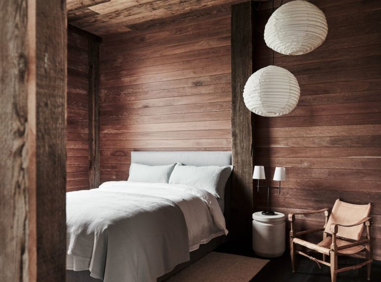 This bedroom is fully clad with wood, there's a comfy bed, some paper lamps and a leather chair