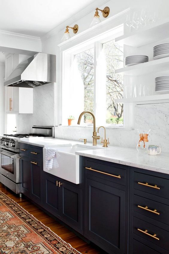 a black kitchen with white stone countertops and a backsplash looks very contrasting