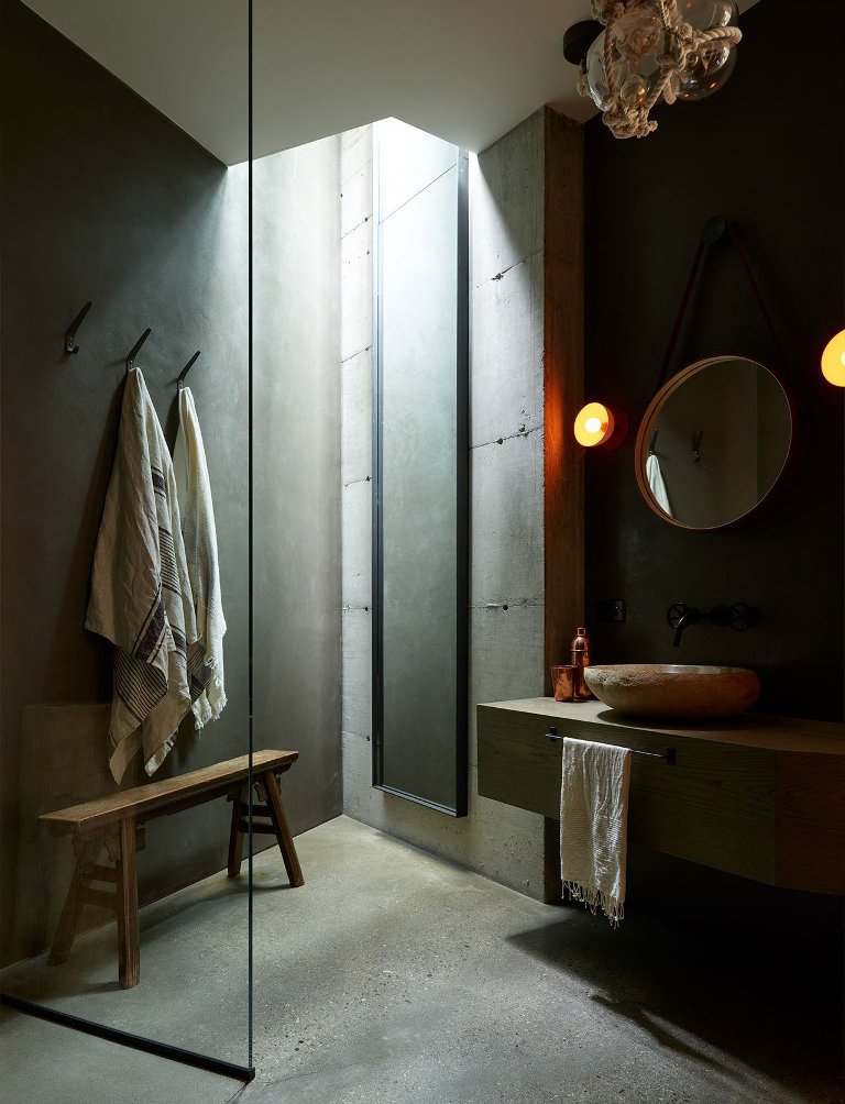 The bathroom features concrete walls and a floor, a stone tub and a floating vanity