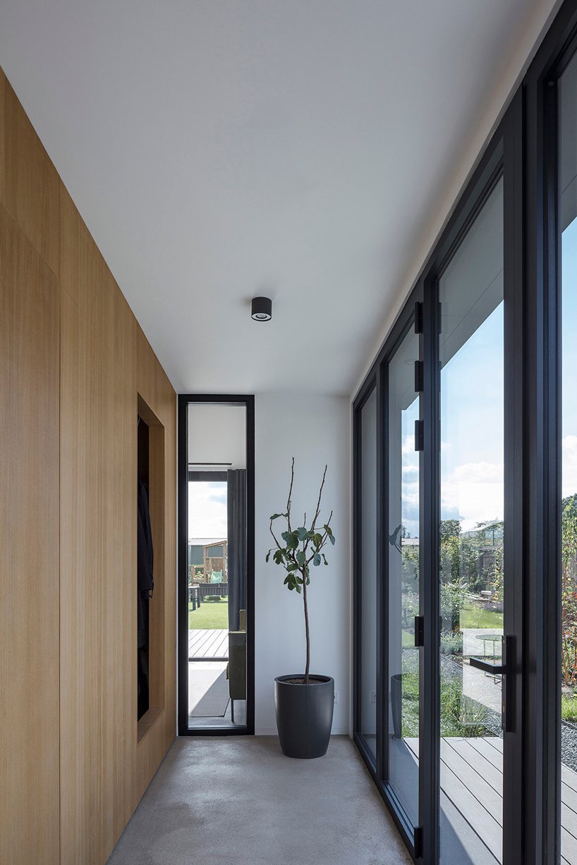 The entryway is minimal, there's a large sleek storage unit and a statement plant in a pot