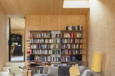 05 The living room is clad with light-colored wood, there are skylights and a wall of books