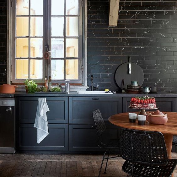 a chic moody kitchen with black marble tiles cladding a whole wall for a refined and bold touch