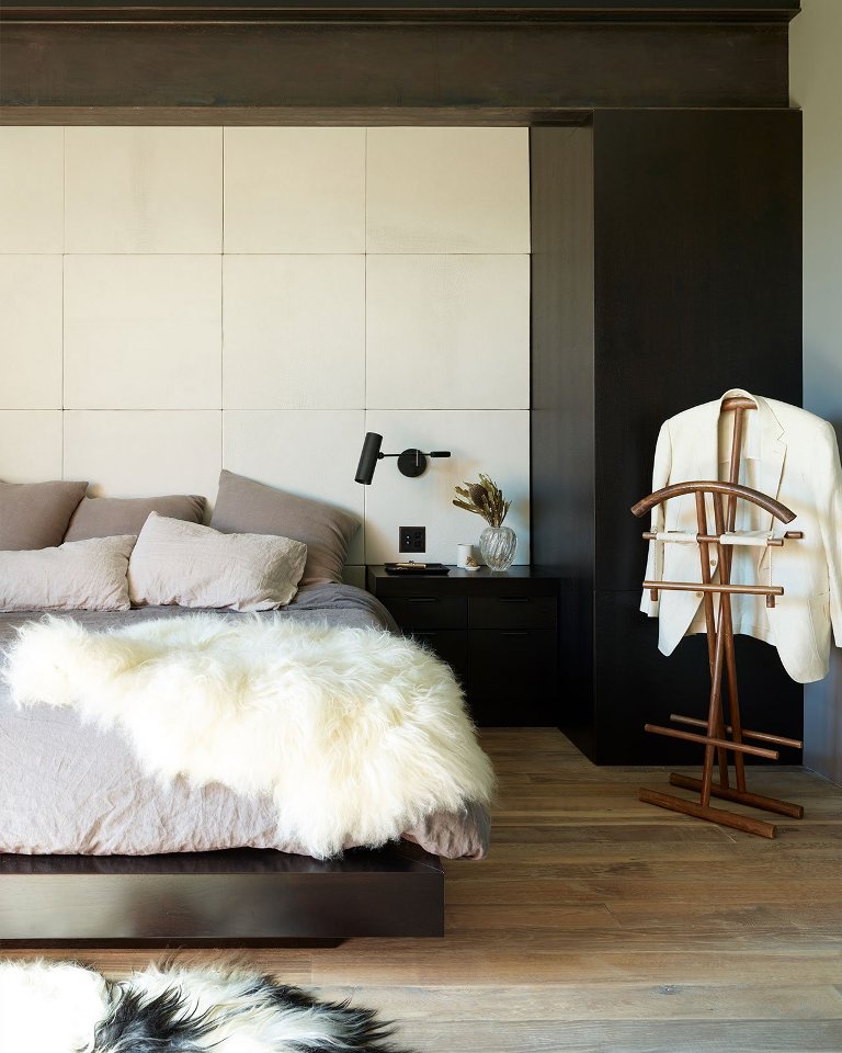 The bedroom shows off a contrasting color schemes, a luxurious bed and sconces