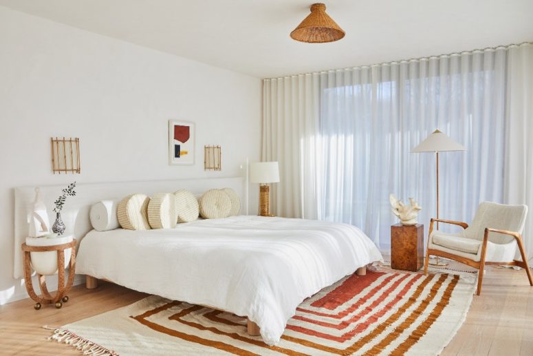 The master bedroom is mid-century modern, mostly neutral but with a striped rug and touches of wicker and stone
