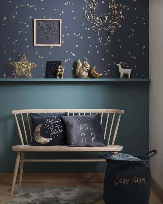 A romantic nook with navy and gold star wallpaper, some stars and moon figurines and matching pillows