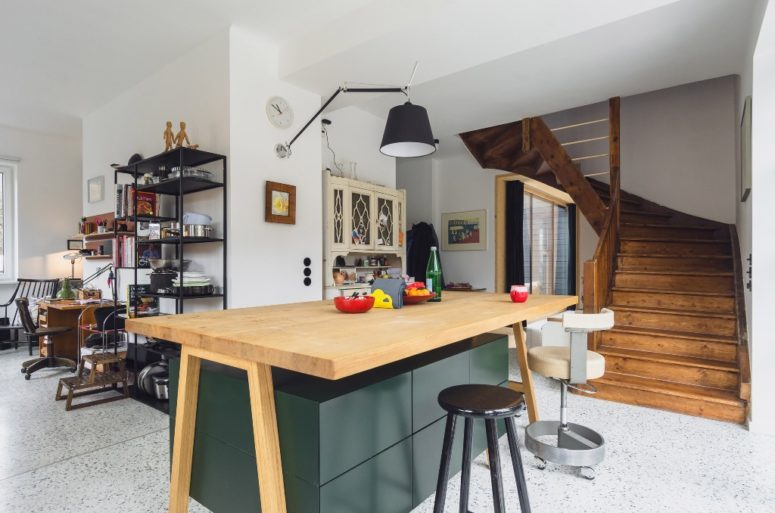 There's a large quirky kitchen island with sleek green drawers and a wooden countertop