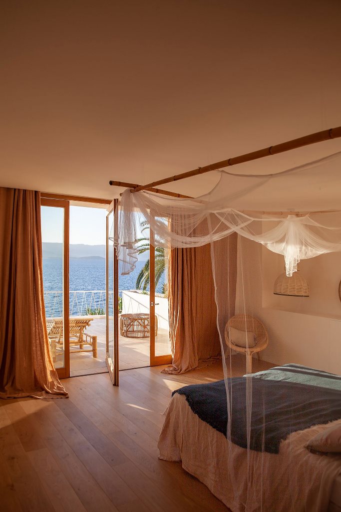 The master bedroom shows off amazing sea views and a large balcony with loungers, a bed with a canopy