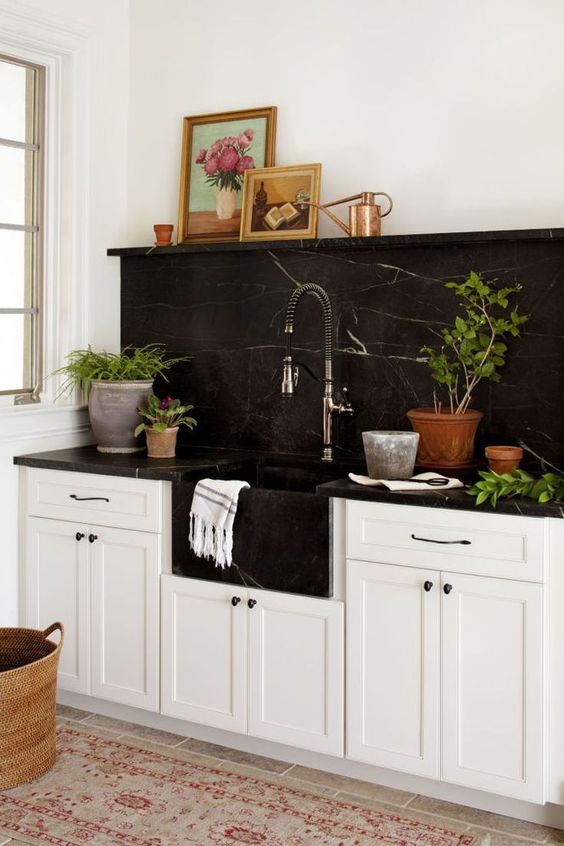 a neutral farmhouse kitchen with a black marble backsplash and coutnertops plus a black built-in sink