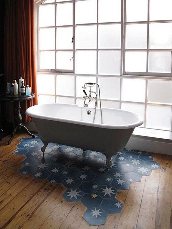 a stylish bathroom with a wooden floor and a blue hex tile with stars floor piece under the tub is gorgeous