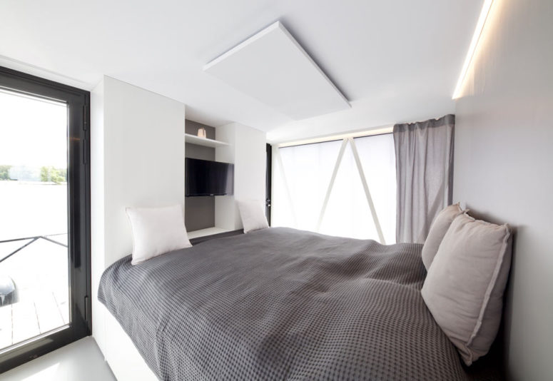 The bedroom features a comfy bed, glazings and a built-in TV on the wall