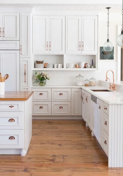 a vintage white kitchen accented with copper hardware to give more color and chic to the space