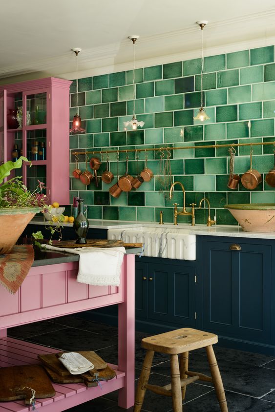 a bright kitchen with navy and pink cabinets and a bright pink kitchen island plus a wooden stool