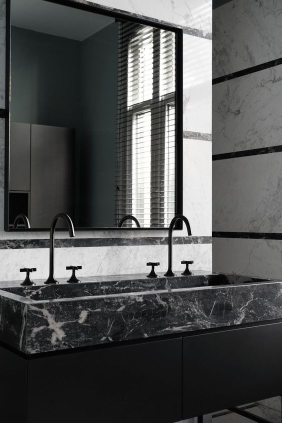a modern moody bathroom with a black marble sink for a refined touch and black matte fixtures for a chic look