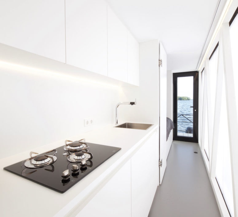 A kitchen is also present, it's done in white, with built-in lights and a comfy surface for cooking