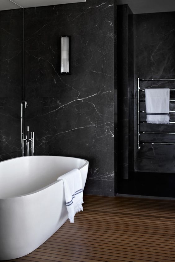 a contemporary bathroom with black marble walls, a wooden slab floor and neutral appliances for a chic look