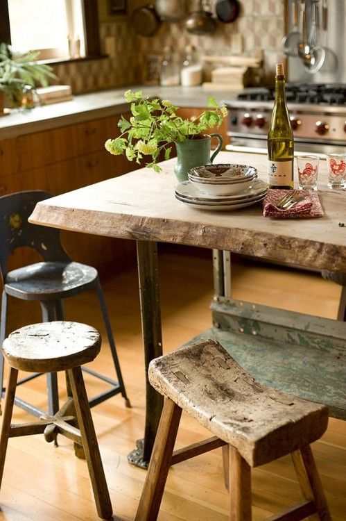 a rough wooden table and kitchen island, with mix and match wooden stools looks very rustic