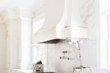 14 a super exquisite white vintage kitchen with a white marble wall and touches of gold looks very elegant and chic